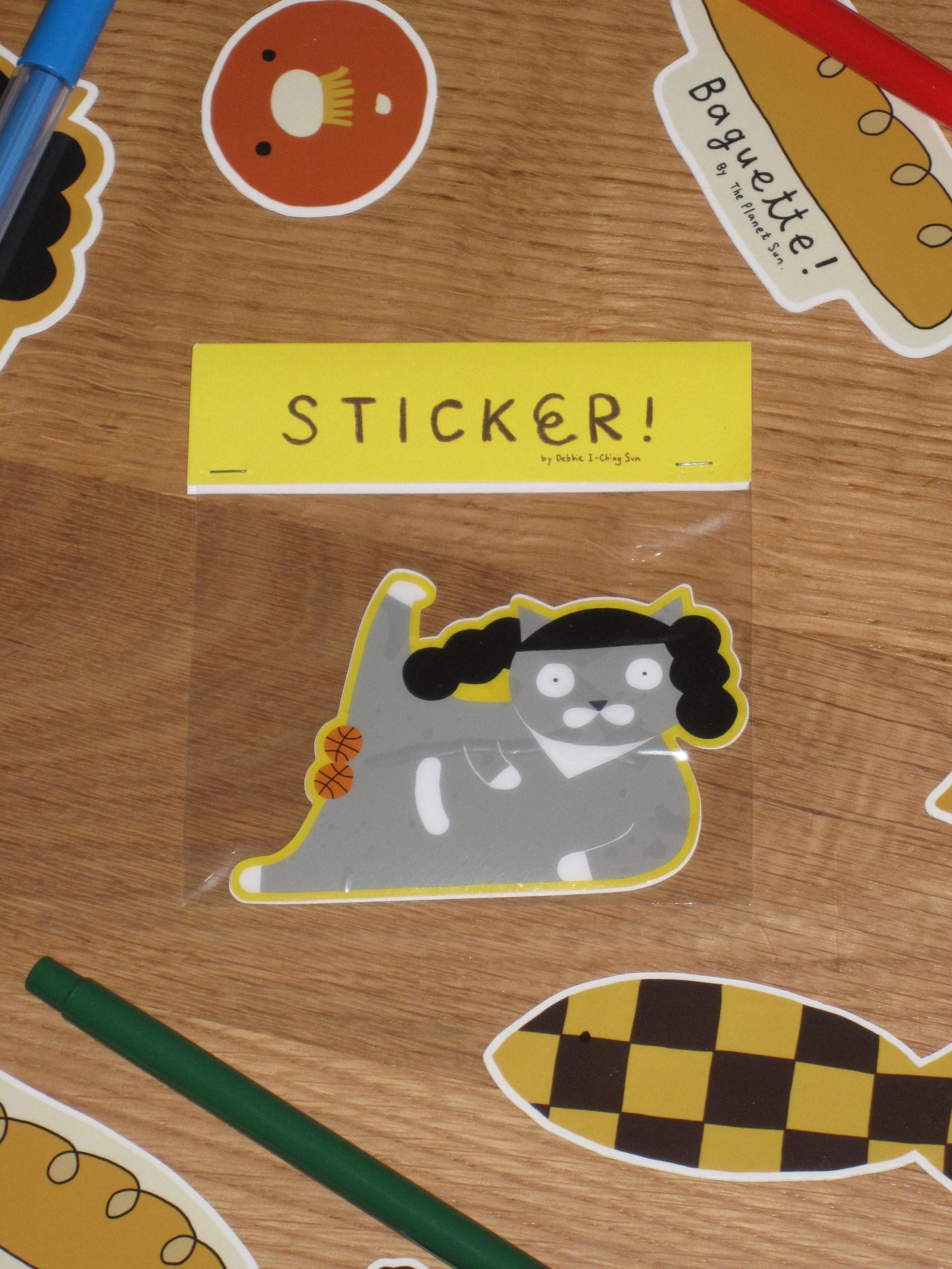 Sticker with a cat design on a wooden surface with other stickers.